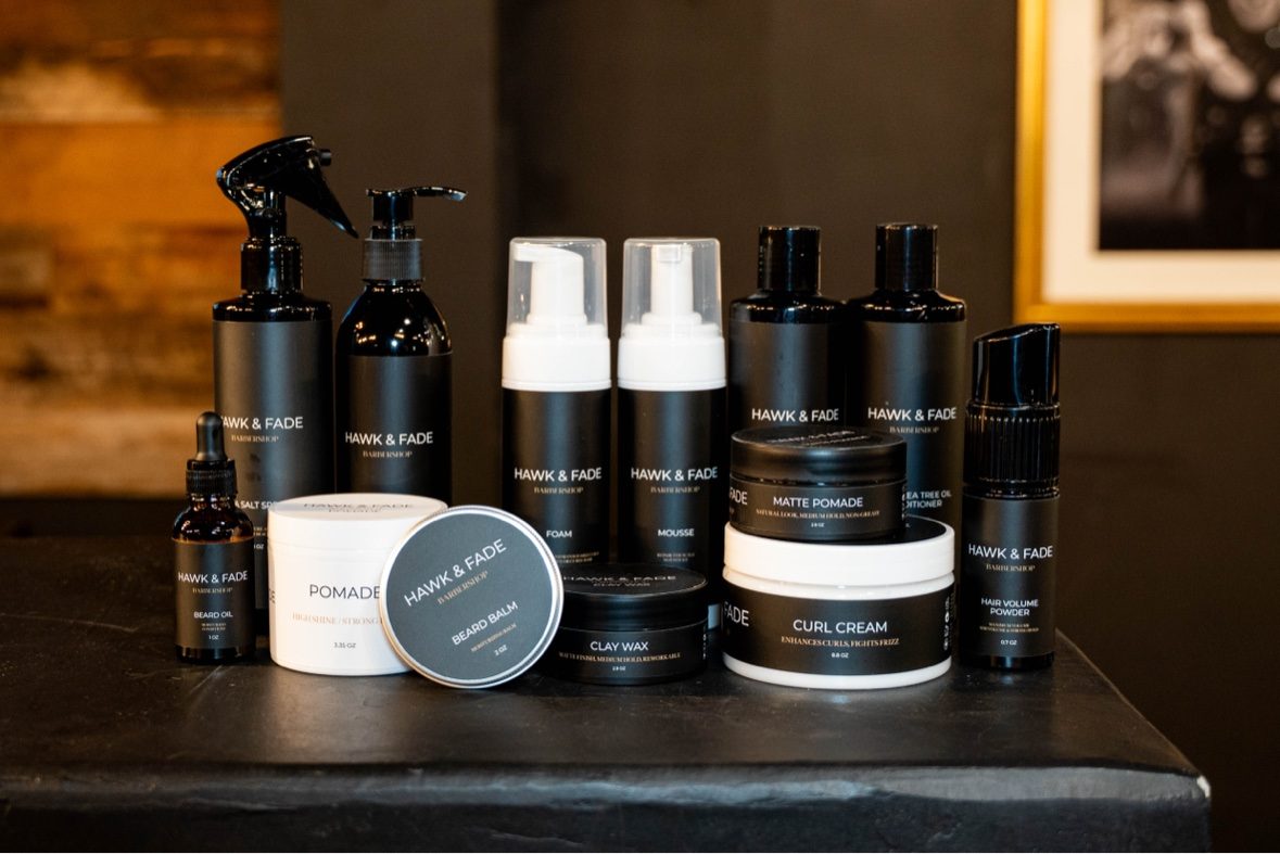Hawk & Fade Supply hair, beard and grooming products arranged together on a dark barber station